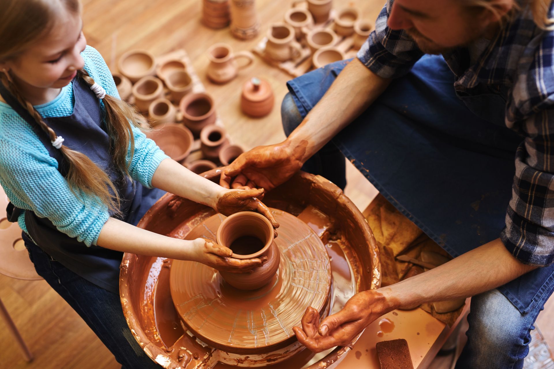 bambina che sta modellando un vaso di argilla insieme ad un maestro