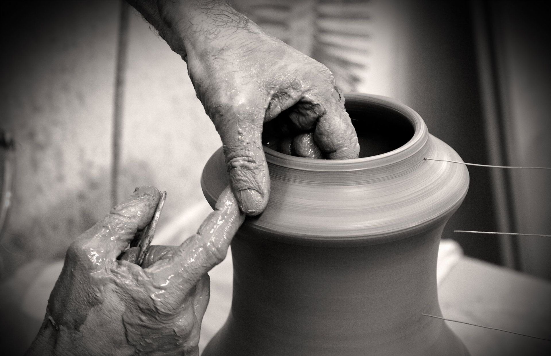 mani che lavorano l'argilla di un vaso sul tornio che ruota
